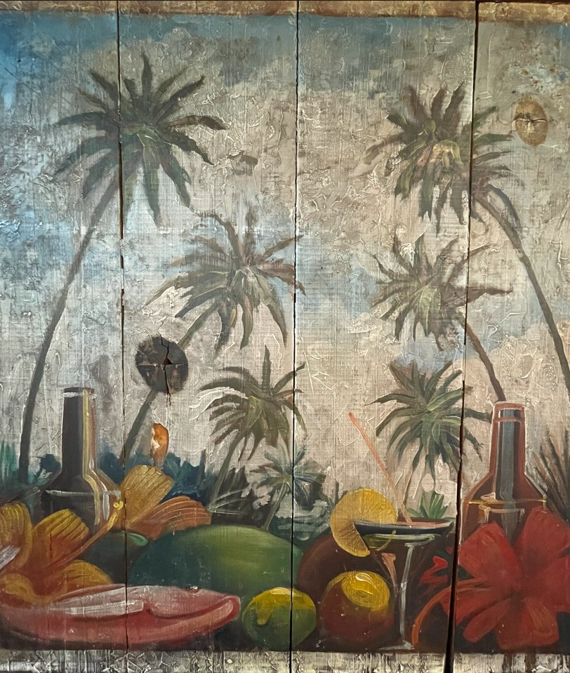 Mural pintado a mano en la sucursal Ventura Puente: palmeras, frutas y cocteles tropicales sobre madera