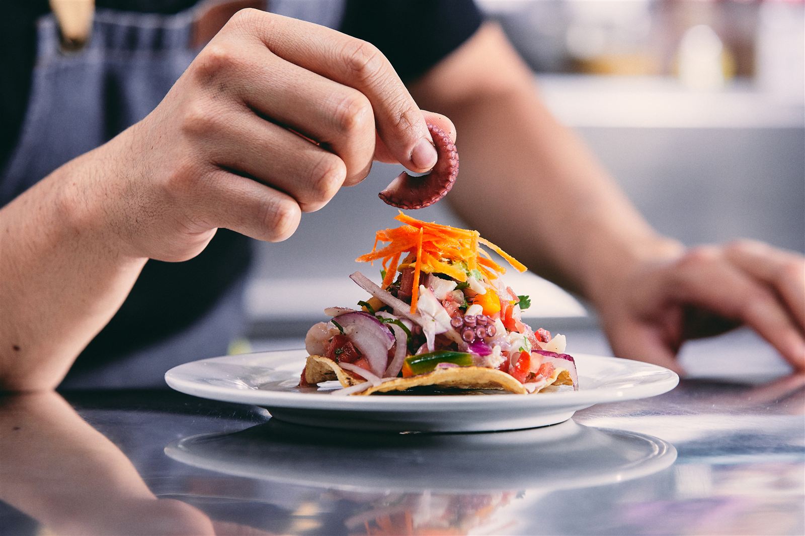 Cocinero montando una tostada de mariscos en la cocina de Salmone's
